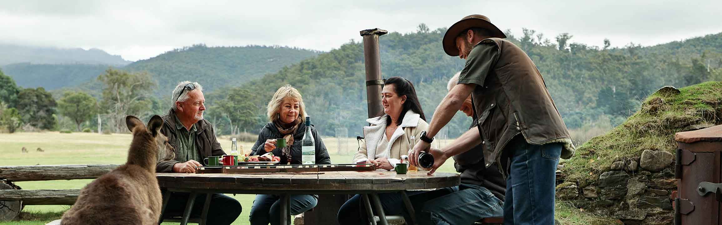 people dining outside with kangaroos