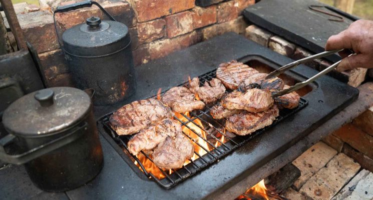outside cooking of beef steaks over the campfire